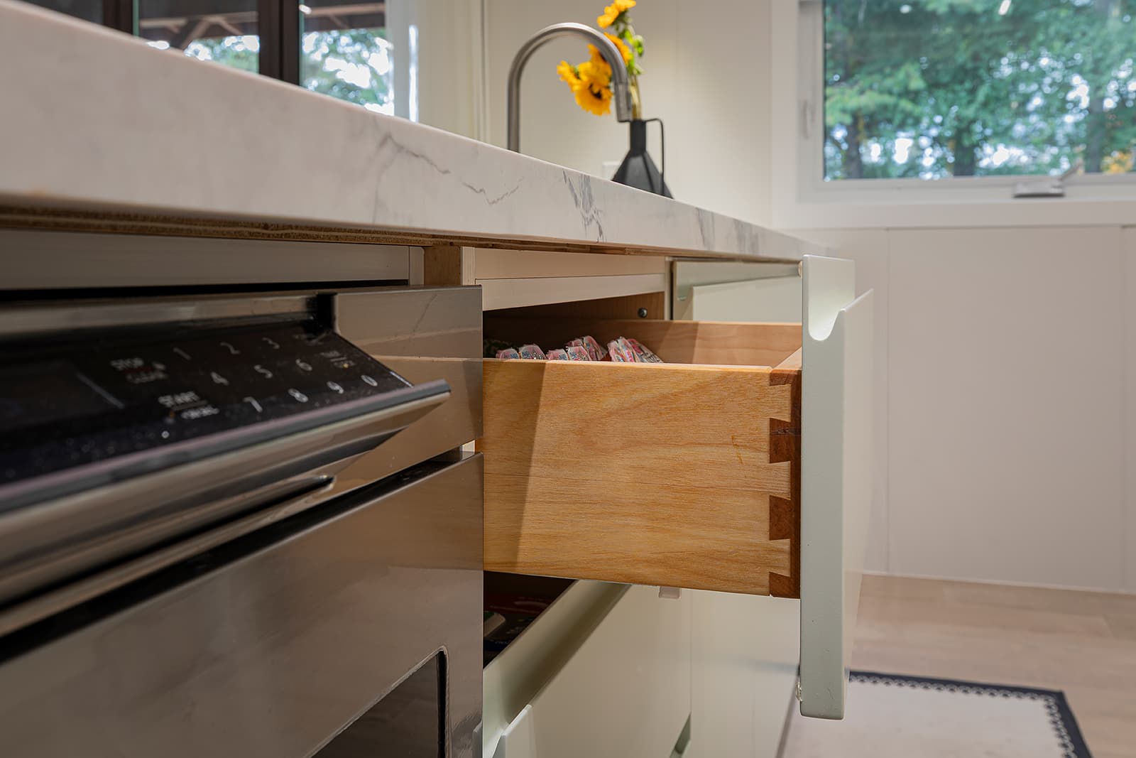 Side view of a modern kitchen drawer with dovetail joints beneath a quartz countertop, showcasing premium cabinetry craftsmanship.