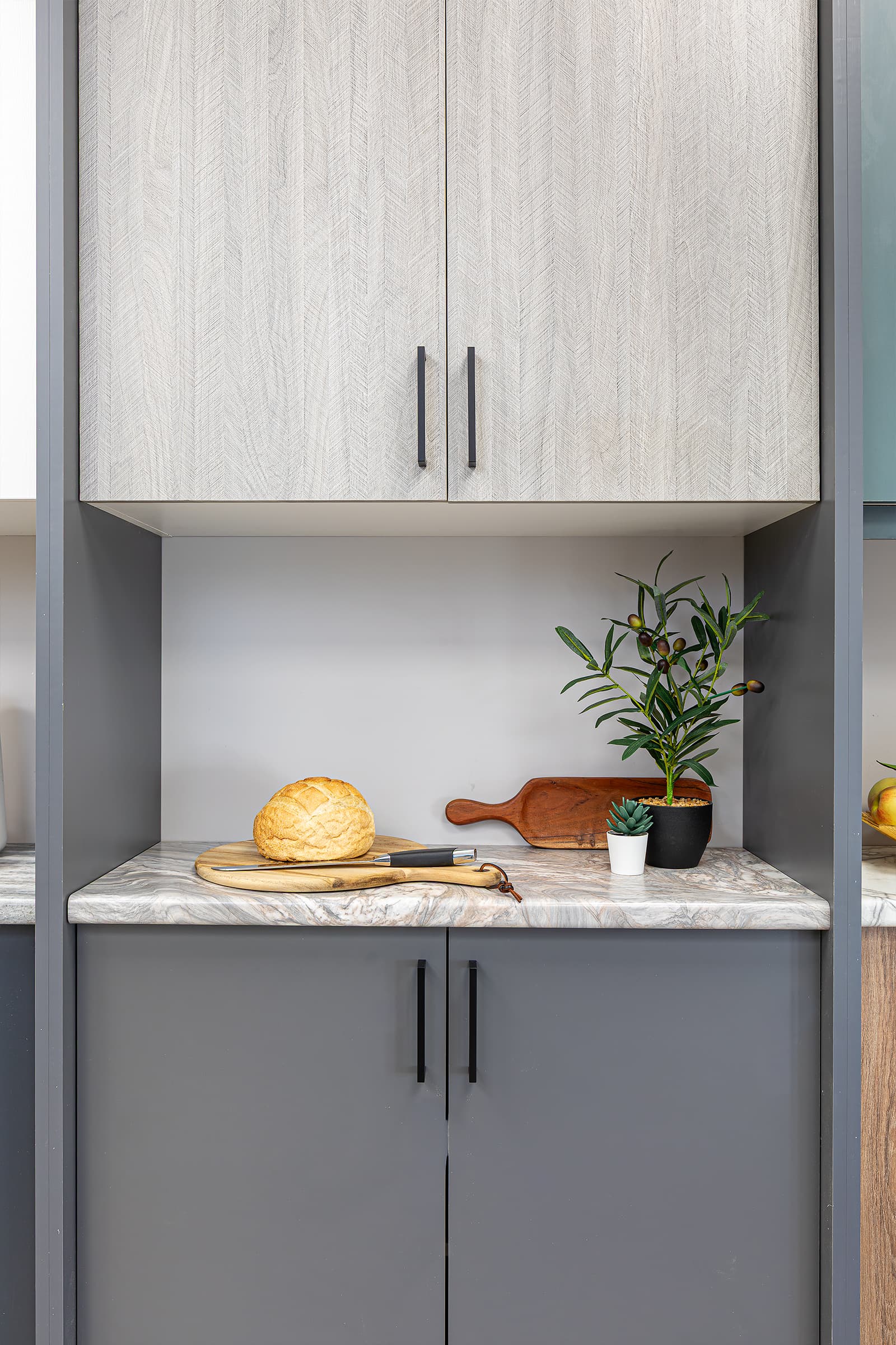 cabinet door and countertop display bread, cutting boards, plant